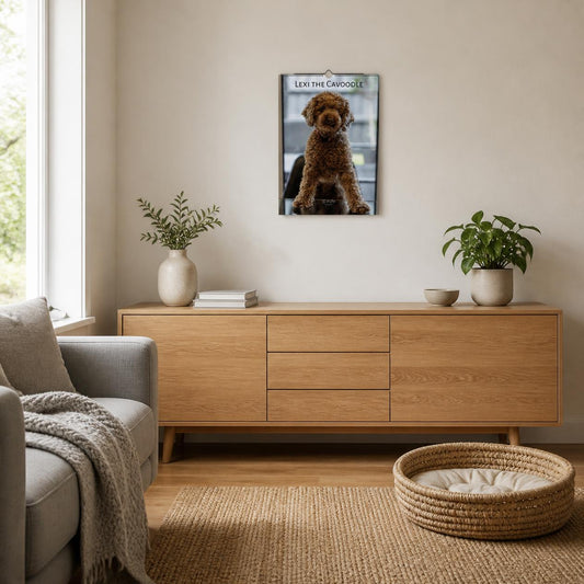 2027 Lexi the Cavoodle wall calendar in A3 size hanging on a living room wall above an oak sideboard, with a woven dog bed on the floor – Istvan Maar Photography