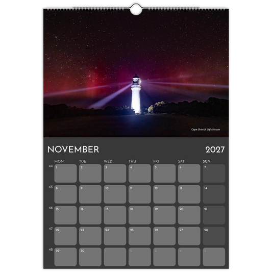 A hanging wall calendar page for November 2027, featuring a night sky lighthouse photograph at the top and a gray monthly calendar grid below.