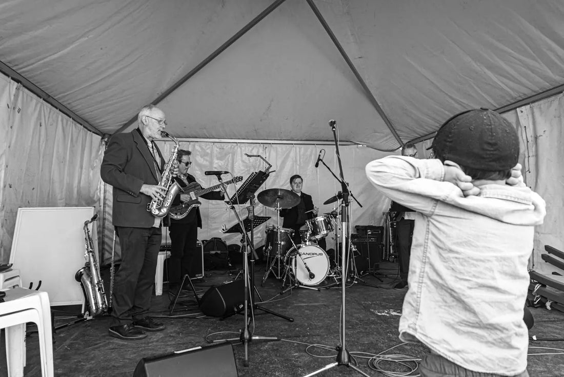 Young boy unimpressed by loud jazz music at Tesselaar Tulip Festival — candid street photography by Istvan Maar