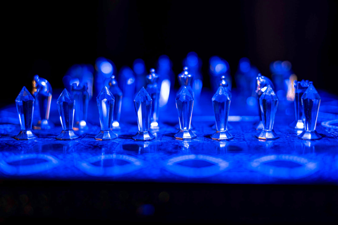 Crystal chess pieces on a board illuminated with blue light