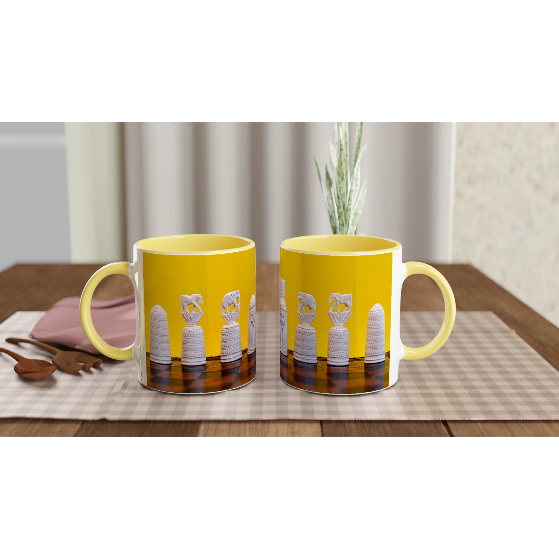 Two yellow ceramic mugs with white handles and a printed design of white bottles on a dark background, displayed on a checkered table mat on a wooden table.