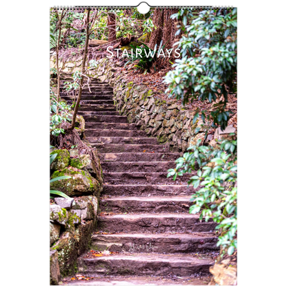 A spiral-bound wall calendar or print featuring a photograph of stone stairways winding through a lush green forest, with the word 'STAIRWAYS' printed across the upper portion.