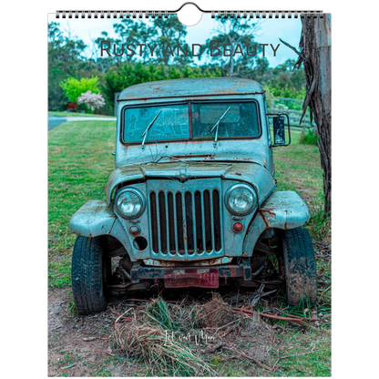 A spiral-bound wall calendar or print featuring an old distressed blue-green jeep parked outdoors on grass and dirt, with the text 'RUSTY AND BEAUTY' across the top. Istvan Maar Photography