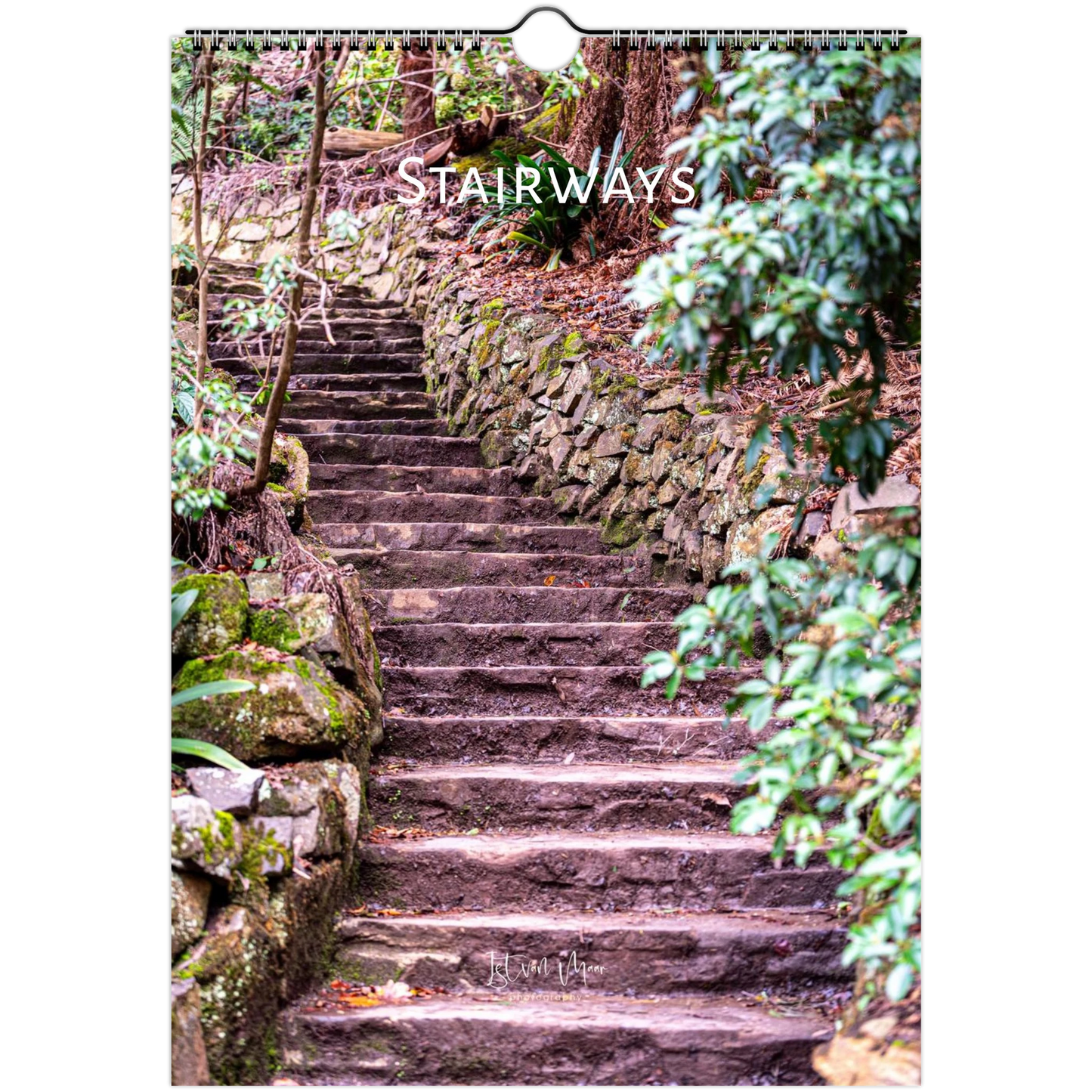 A vertical wall calendar page showing a stone stairway winding through a forest with mossy rocks and green foliage. The word 'STAIRWAYS' appears across the upper middle in white text, and the calendar has a hanging ring at the top.