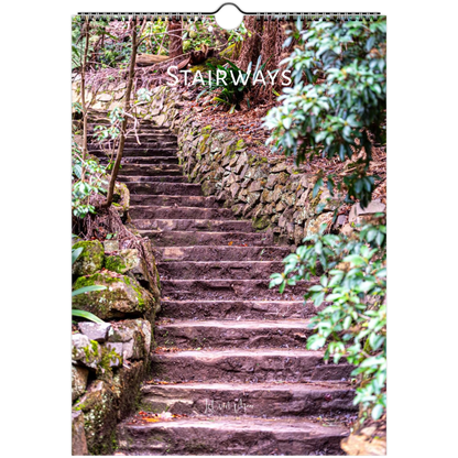 A vertical wall calendar page showing a stone stairway winding through a forest with mossy rocks and green foliage. The word 'STAIRWAYS' appears across the upper middle in white text, and the calendar has a hanging ring at the top.