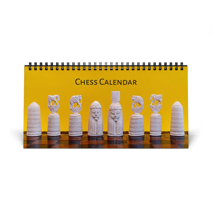 A spiral-bound desk calendar titled 'CHESS CALENDAR' with a bright yellow cover showing a row of white carved chess pieces on a dark wooden surface, photographed on a white background.