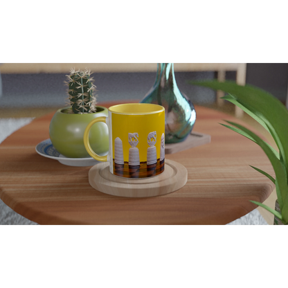 A yellow ceramic mug with a handle, featuring a graphic of four white bottles on a dark brown background, resting on a round wooden coaster on a wooden table. The background is a styled interior scene with a small potted cactus and other decor.