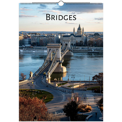 A vertical wall calendar page titled "BRIDGES" showing a scenic photograph of a suspension bridge over a river with city buildings in the background, photographed against a white surround.