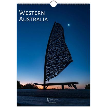 A spiral-bound wall calendar or poster featuring a scenic photograph of Western Australia at dusk. The design shows a dark silhouette of a windsurf board against a deep blue twilight sky with a small bright moon.