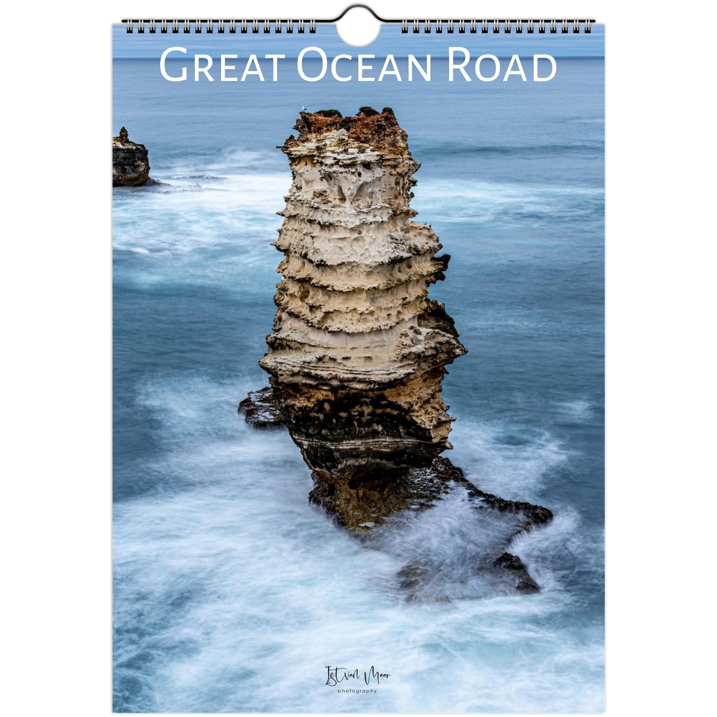 A spiral-bound wall calendar or print titled "Great Ocean Road" showing a coastal rock formation rising from blue ocean water, with the text "Great Ocean Road" across the top and a small artist signature near the bottom.