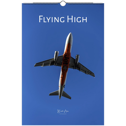 A hanging wall calendar cover featuring a photograph of a jet airplane flying upward against a clear blue sky, with the title 'FLYING HIGH' at the top.