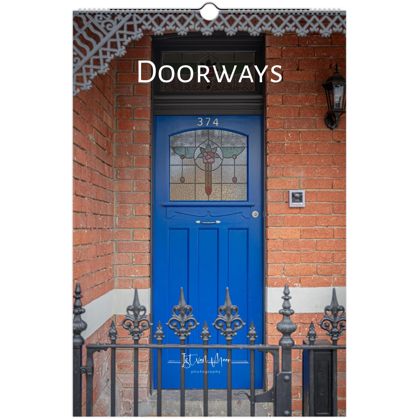 A vertical wall art print or poster featuring a photograph of a bright blue front door set in a red brick building, with the word 'Doorways' printed across the top. A small script signature appears near the bottom.