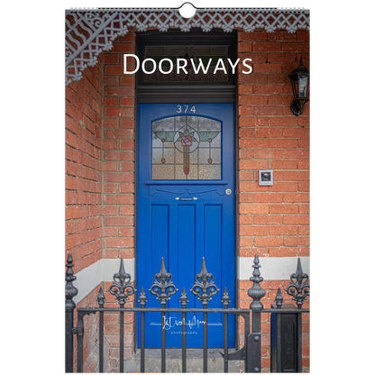 A vertical wall art print or poster featuring a photograph of a bright blue front door set in a red brick building, with the word 'Doorways' printed across the top. A small script signature appears near the bottom.