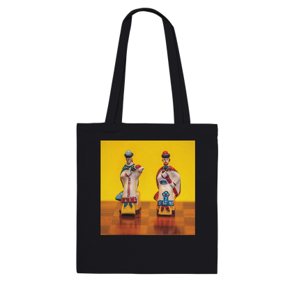 A black canvas tote bag with two shoulder straps, featuring a square graphic print on the front. The print shows two stylized, colorful figures resembling traditional Russian porcelain figurines against a bright yellow background and a brown checkered floor.