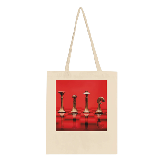 A natural canvas tote bag with long shoulder straps, featuring a square graphic print on the front of four metallic chess pieces against a vivid red background.