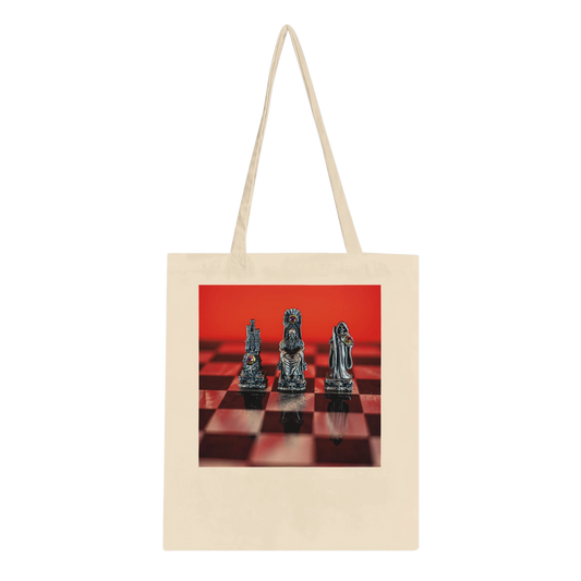 A natural canvas tote bag with long handles, featuring a rectangular printed graphic on the front of three metallic chess pieces on a red and black checkered board against a solid red background.