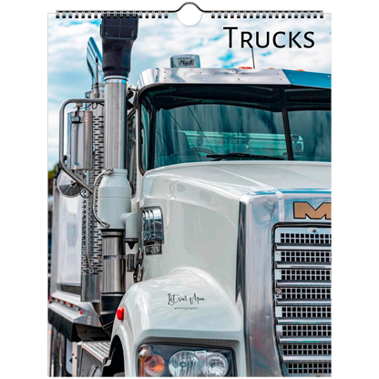 A spiral-bound wall calendar page featuring a close-up photograph of a white Mack truck under a blue sky, with the word "TRUCKS" printed at the top.