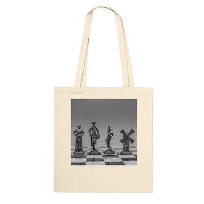 A natural canvas tote bag with a square black-and-white photographic print on the front showing chess pieces on a chessboard, set against a plain white background.