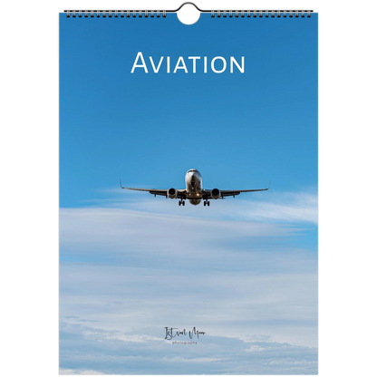 A spiral-bound wall calendar featuring an aviation theme, with a blue sky background, an airplane flying overhead, and the word 'AVIATION' printed at the top.
