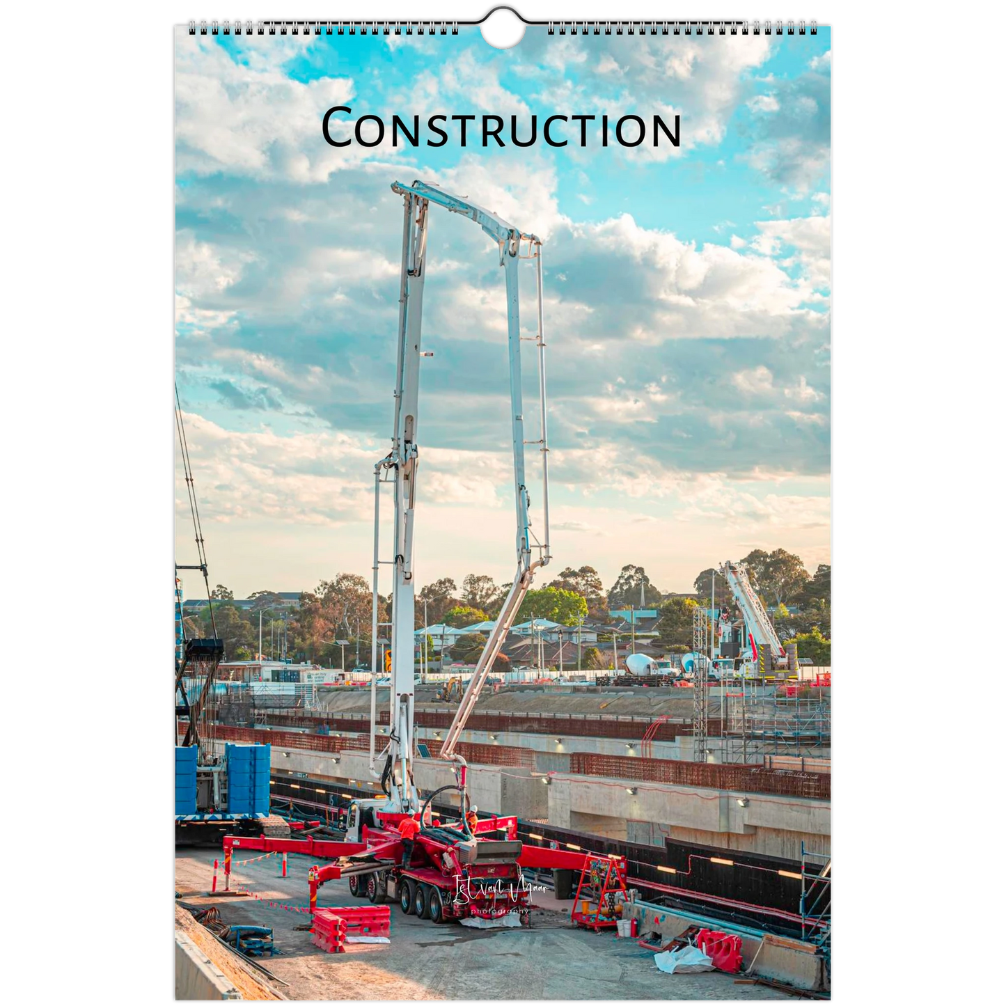 A spiral-bound wall calendar page featuring a construction site scene with a large concrete pump, cloudy sky, and the word "CONSTRUCTION" printed at the top.