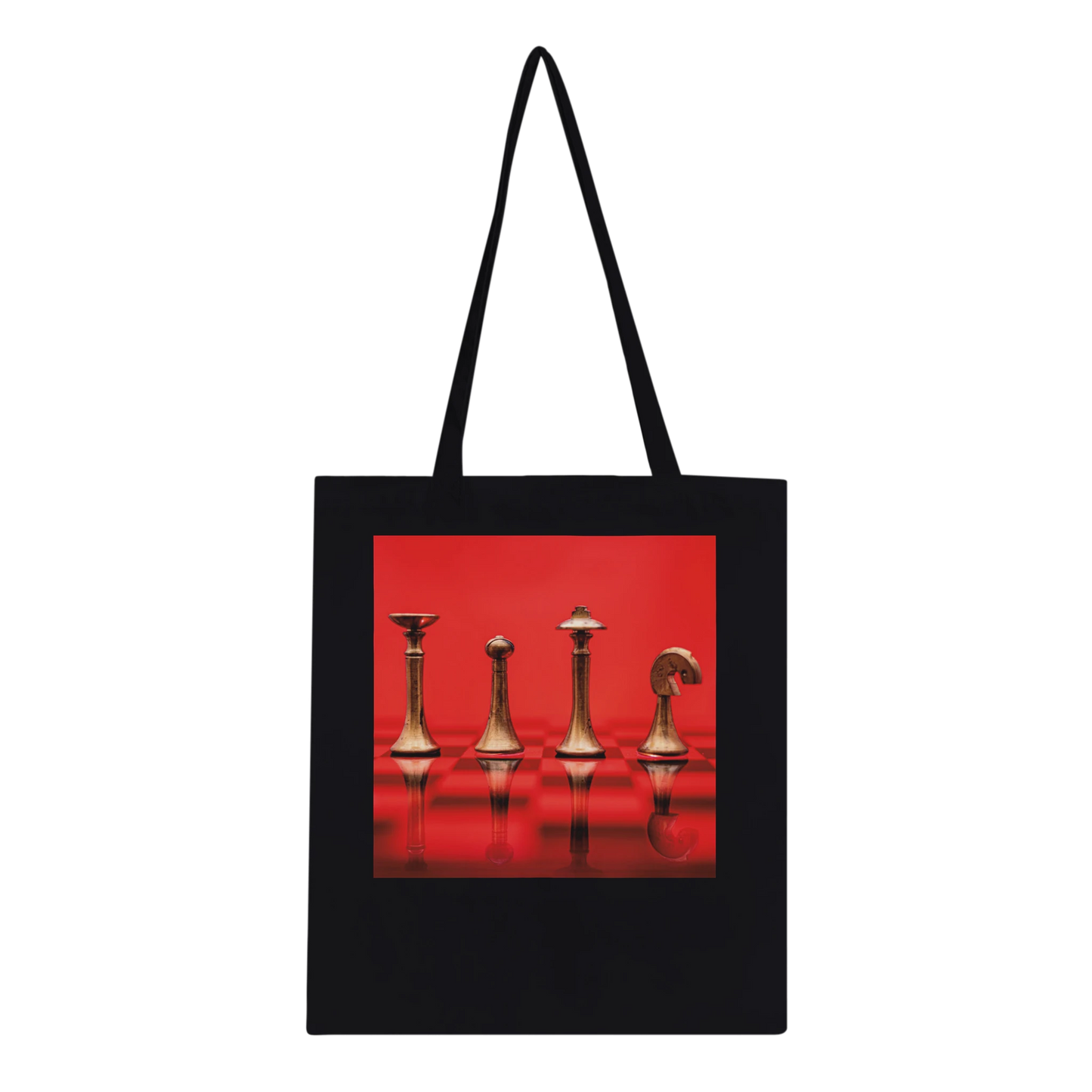 A black canvas tote bag with black shoulder straps, featuring a square graphic print on the front of four metallic chess pieces against a vivid red background.