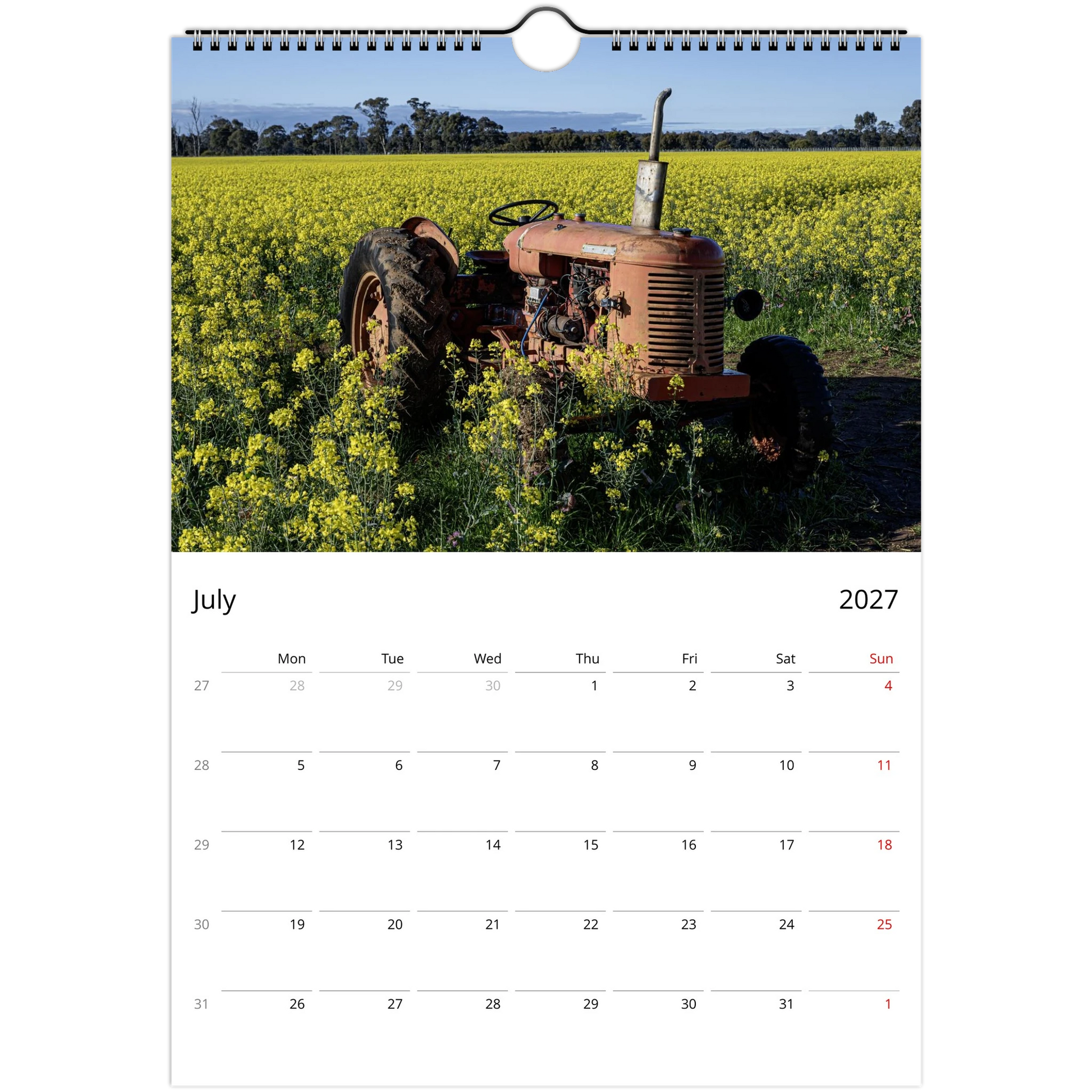 A single-page wall calendar spread showing a photograph of an old orange tractor in a yellow flower field on the top page, with a July 2027 calendar grid on the bottom page against a white background.