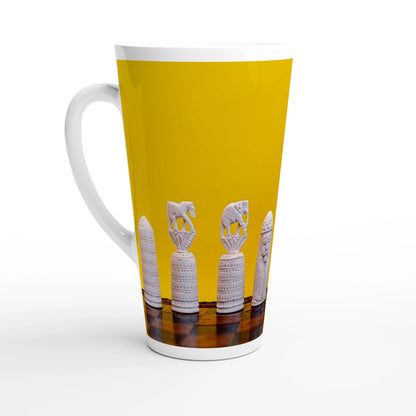 A white ceramic latte mug with a handle, featuring a wrap-around graphic print of white carved chess pieces against a bright yellow background.