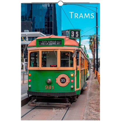 A vertical wall calendar page featuring a vintage green and cream tram on a city street, with the title 'TRAMS' printed at the top right. The calendar has a hanging ring at the top and a printed photo of the street scene on the front.