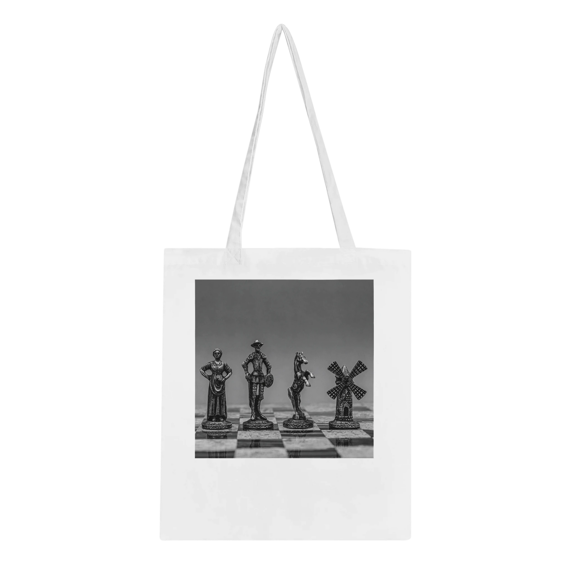 A white canvas tote bag with long shoulder straps, featuring a black and white photographic print of four chess pieces on a chessboard. The bag is shown against a plain white background.