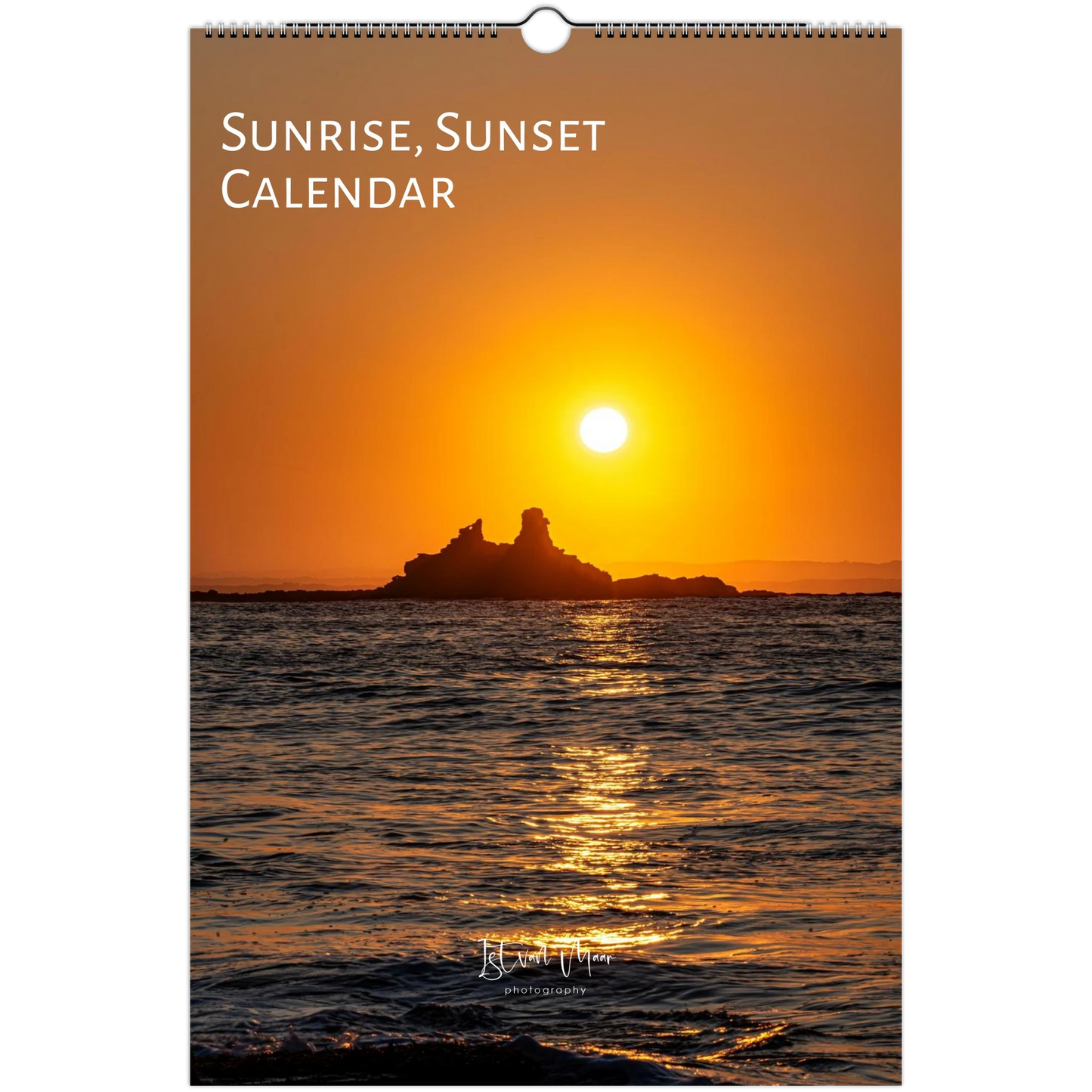 A wall calendar titled 'Sunrise, Sunset Calendar' featuring a scenic photograph of a bright sun over the ocean with a dark rocky island silhouette and golden reflections on the water.