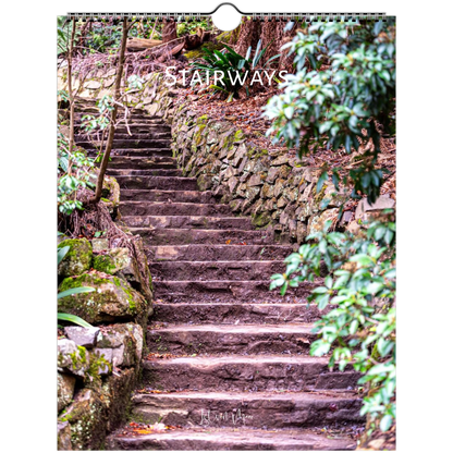 A wall calendar page featuring a photograph of stone stairways winding through a lush green forest. The title 'STAIRWAYS' is printed across the top in white, and the calendar hangs from a metal ring at the top.