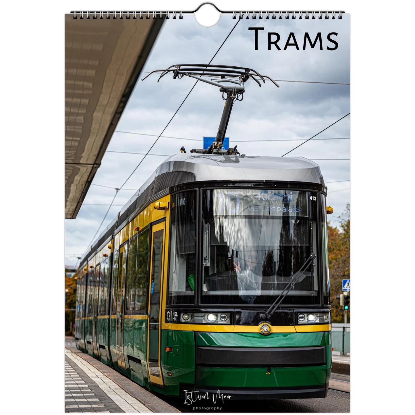 A spiral-bound wall calendar or print featuring a photograph of a green and yellow tram at a station platform under an overcast sky, with the word "TRAMS" printed at the top. Available in A4, A3, LT and LG US sizes.