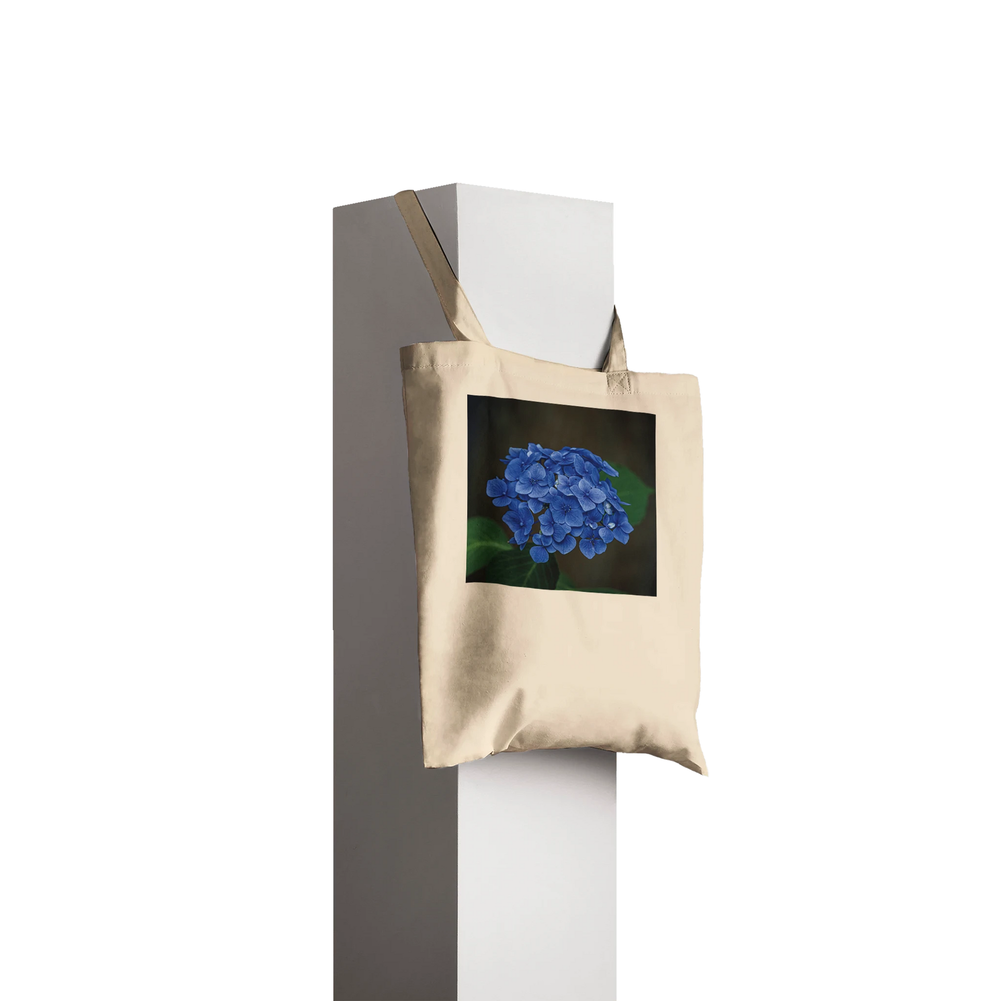 Natural canvas tote bag printed with a blue hydrangea photograph, Classic style, hanging profile view