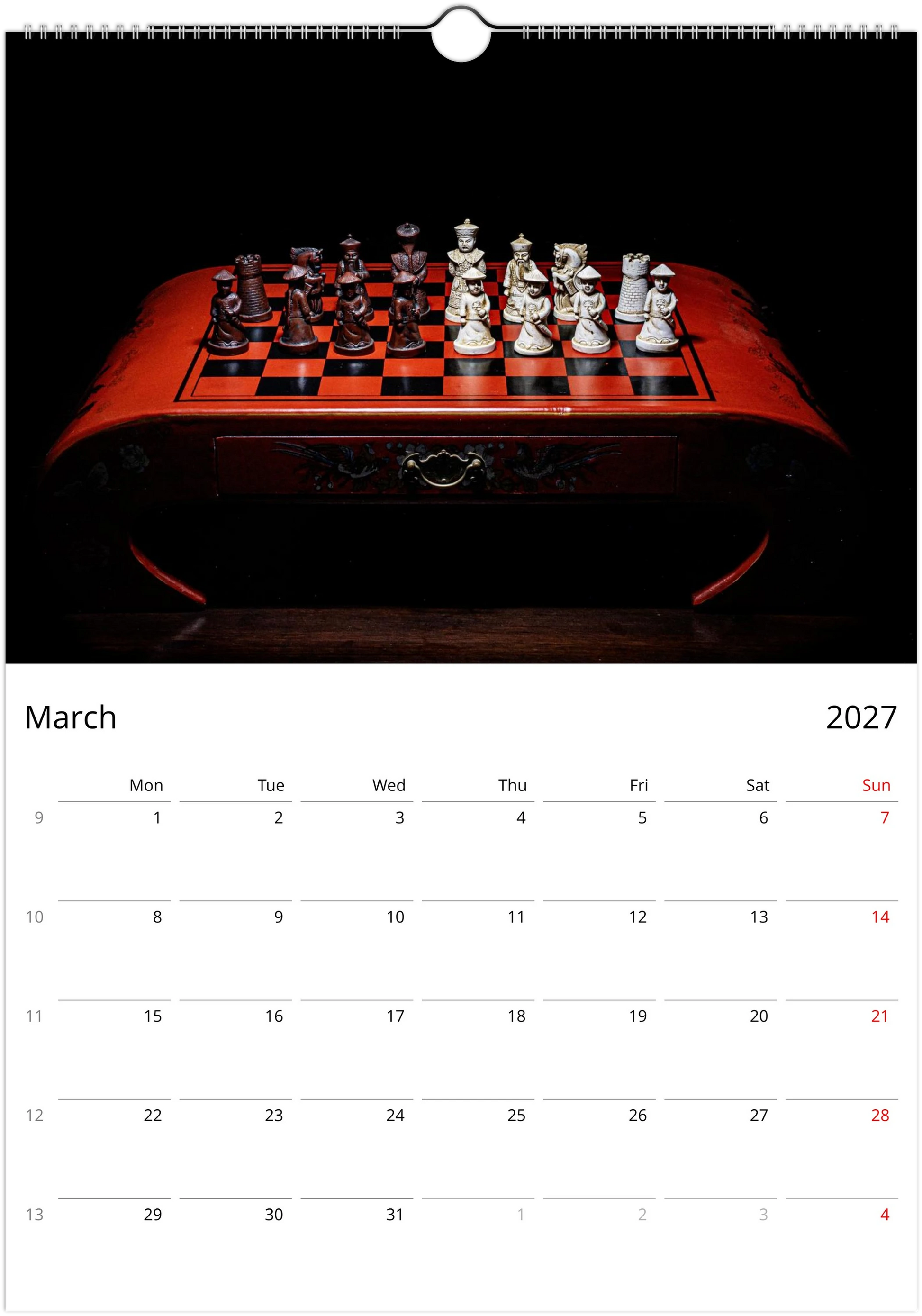 A wall calendar page showing March 2027, with a large black-and-red chessboard photograph at the top and a calendar grid below.