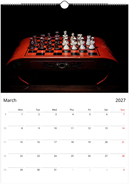 A wall calendar page showing March 2027, with a large black-and-red chessboard photograph at the top and a calendar grid below.