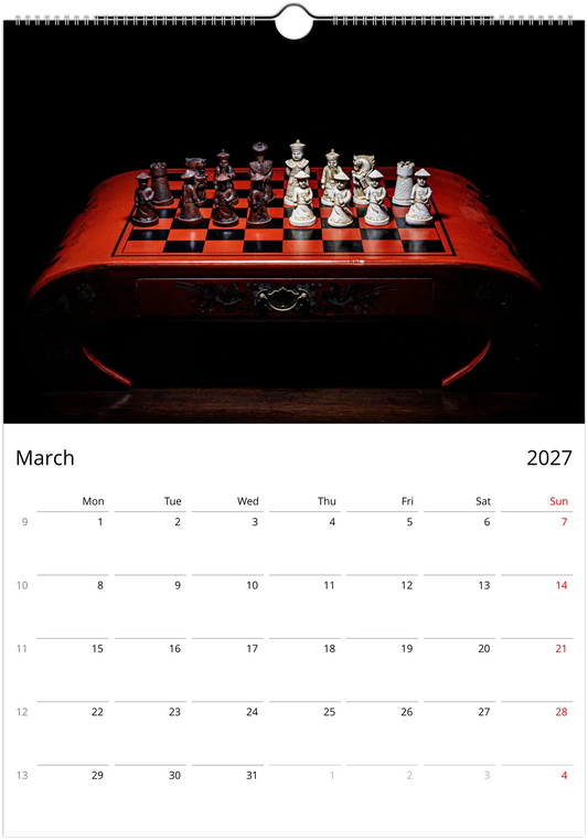 A wall calendar page showing March 2027, with a large black-and-red chessboard photograph at the top and a calendar grid below.