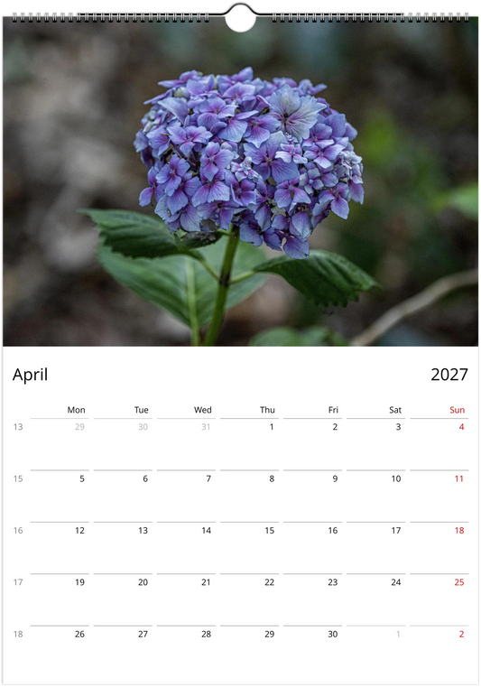 Calendar page for April 2027 with a purple flower on a blurred natural background