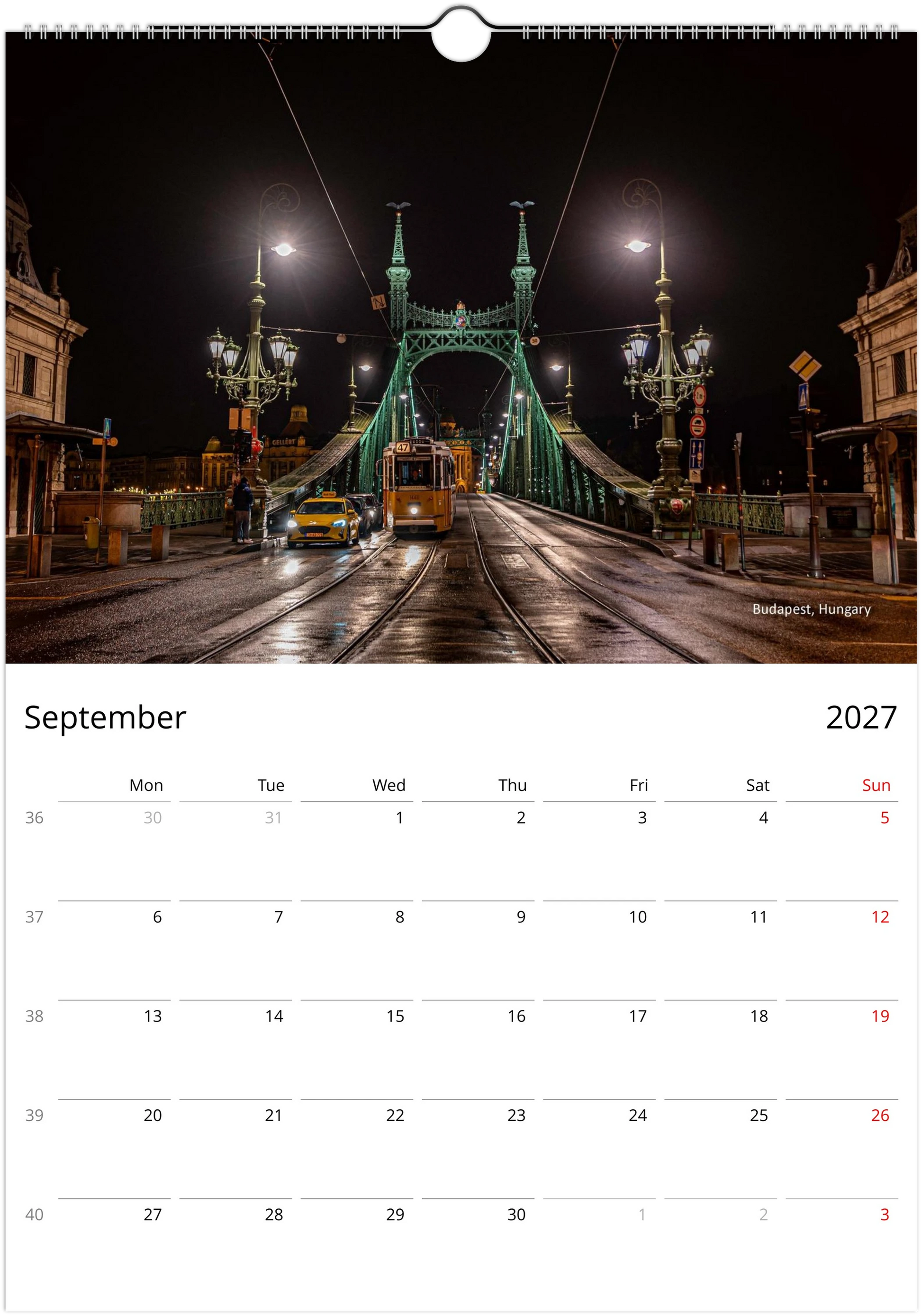 Yellow Budapest tram crossing Liberty Bridge at night ornate green iron bridge lit by street lamps reflecting on wet cobblestones - Budapest Hungary - Trams After Dark wall calendar September