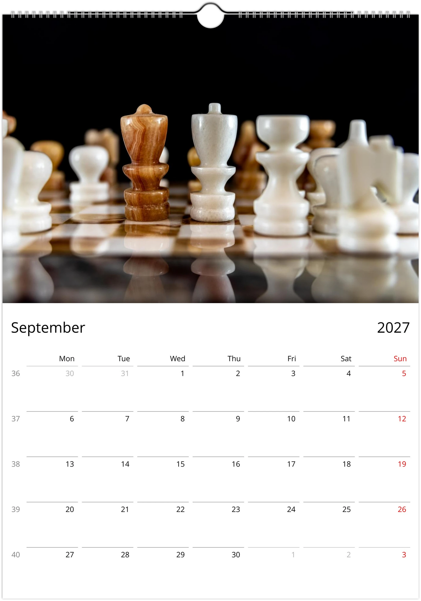 A September 2027 wall calendar page featuring a close-up photograph of chess pieces on a reflective chessboard, with a white grid layout for the days of the week below.