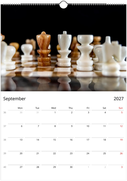 A September 2027 wall calendar page featuring a close-up photograph of chess pieces on a reflective chessboard, with a white grid layout for the days of the week below.