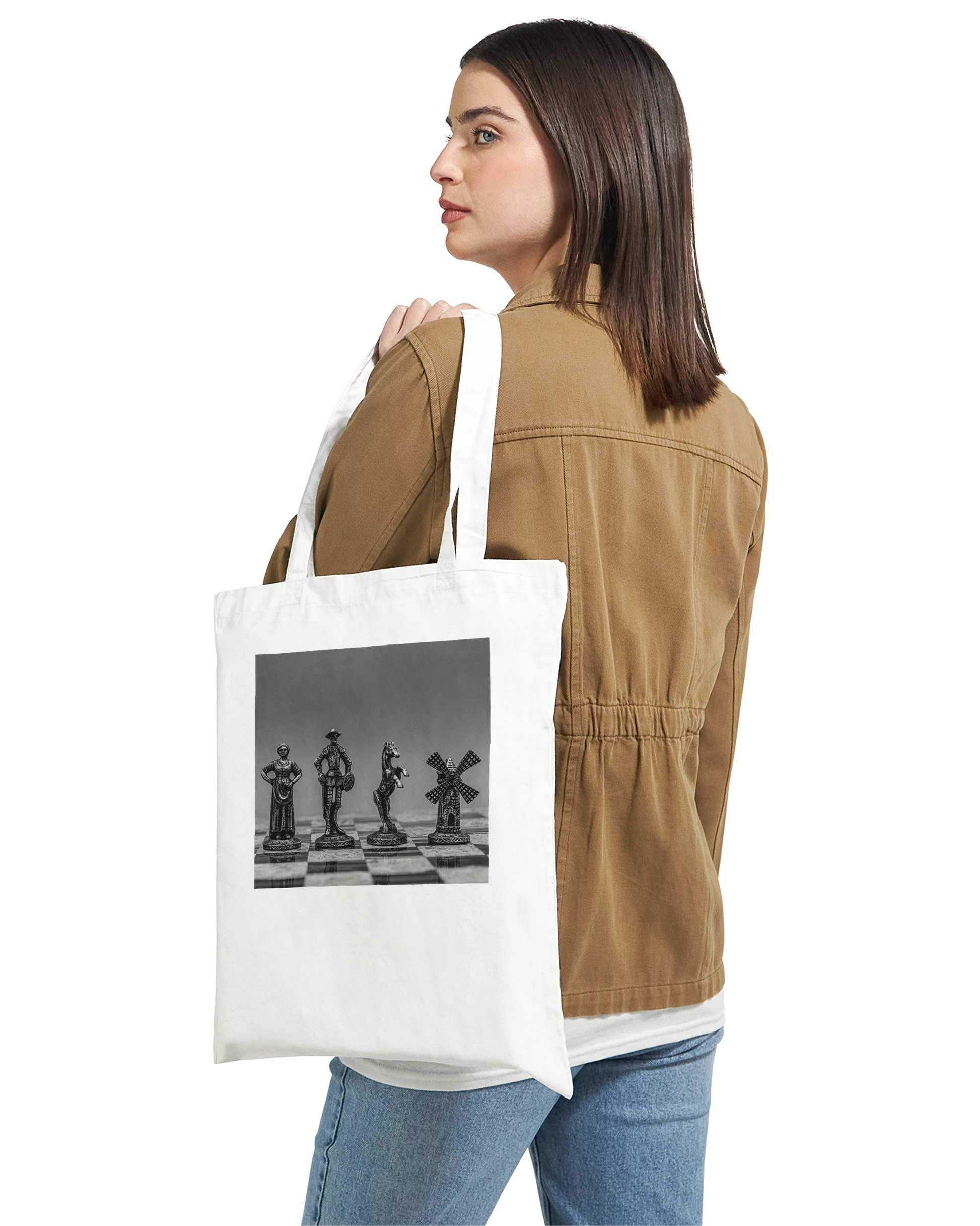 A woman wearing a brown jacket and blue jeans is shown from the back, carrying a white canvas tote bag over her shoulder. The tote bag features a black and white graphic print of chess pieces on a chessboard.