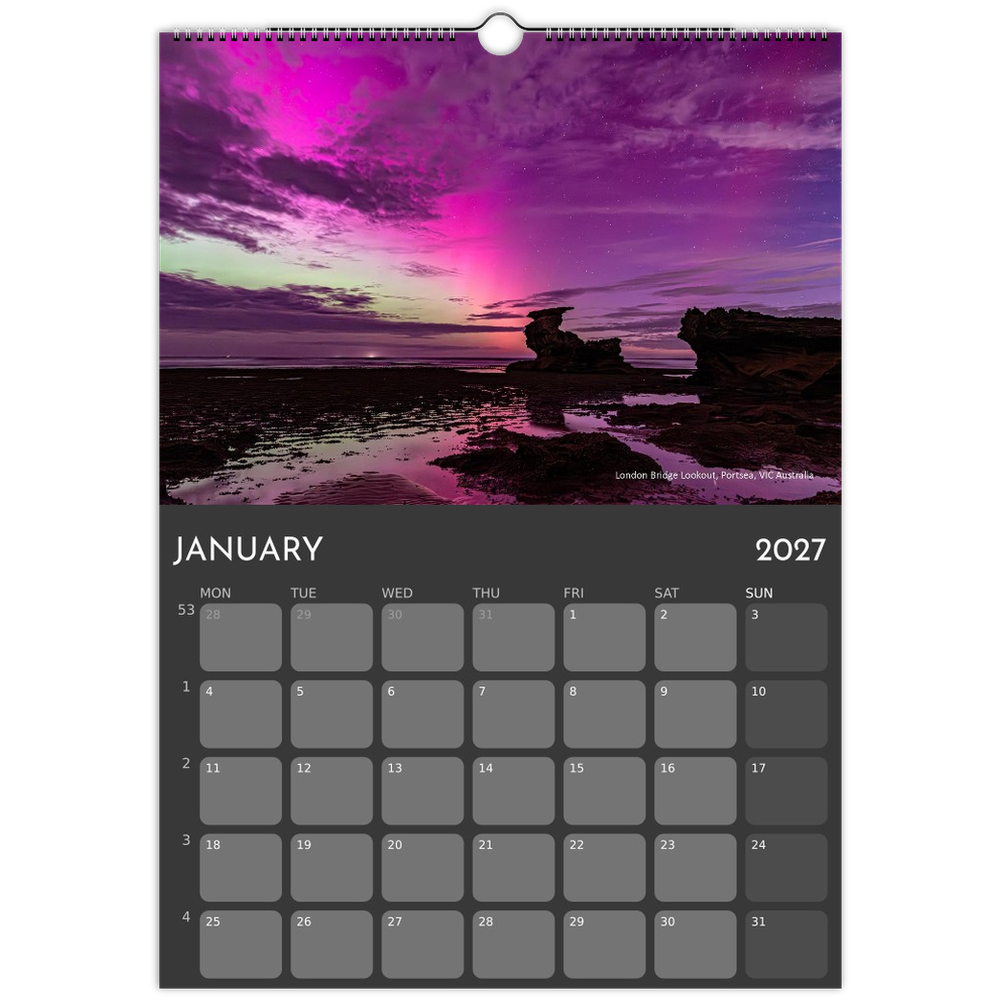 A single-page wall calendar spread showing January 2027 with a large scenic photograph of a purple and pink sunset sky over coastal rocks, plus a dark calendar grid below.