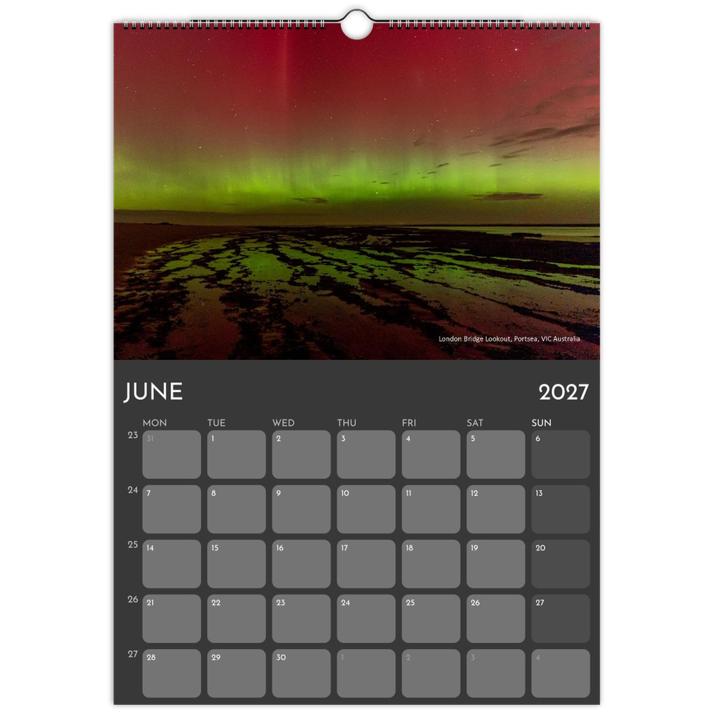A single-page wall calendar spread showing the month of June 2027, with a dark gray grid at the bottom and a large photograph of northern lights over a coastal landscape at the top.
