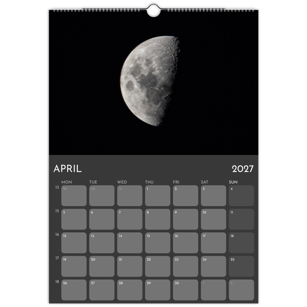 A hanging wall calendar page showing a black-and-white moon photograph on a black background, with the calendar grid for April 2027 below.