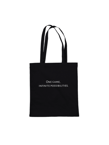 A black canvas tote bag with black shoulder straps and a small white printed slogan on the front reading 'One game, infinite possibilities'. The bag is photographed against a plain white background.