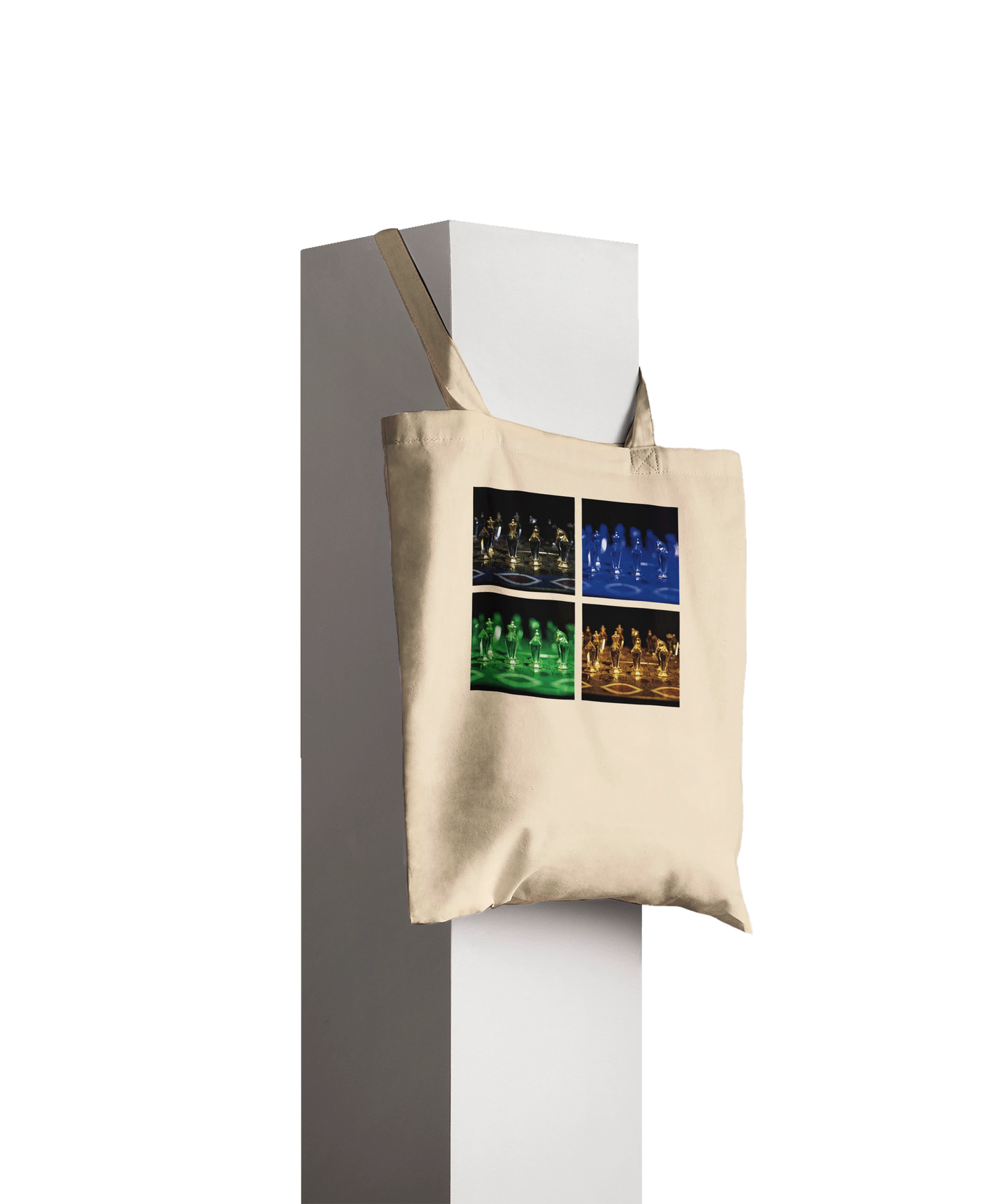 A beige canvas tote bag with a four-panel graphic print of chess players in different colored lighting, hanging from a white display stand against a dark gray background.