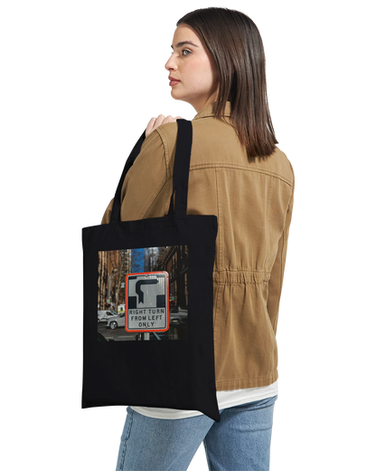 Model carrying the Premium Black Right Turn street sign tote bag over one shoulder, lifestyle shot