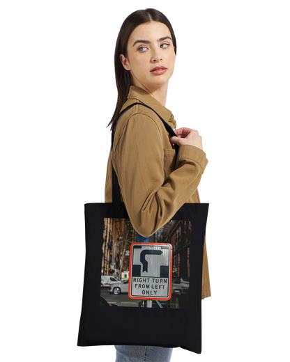 Model wearing the Premium Black Right Turn street sign tote bag, side profile lifestyle shot