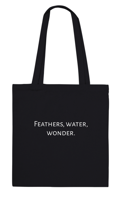 Black canvas tote bag with personalised 'Feathers, water, wonder.' text on the back