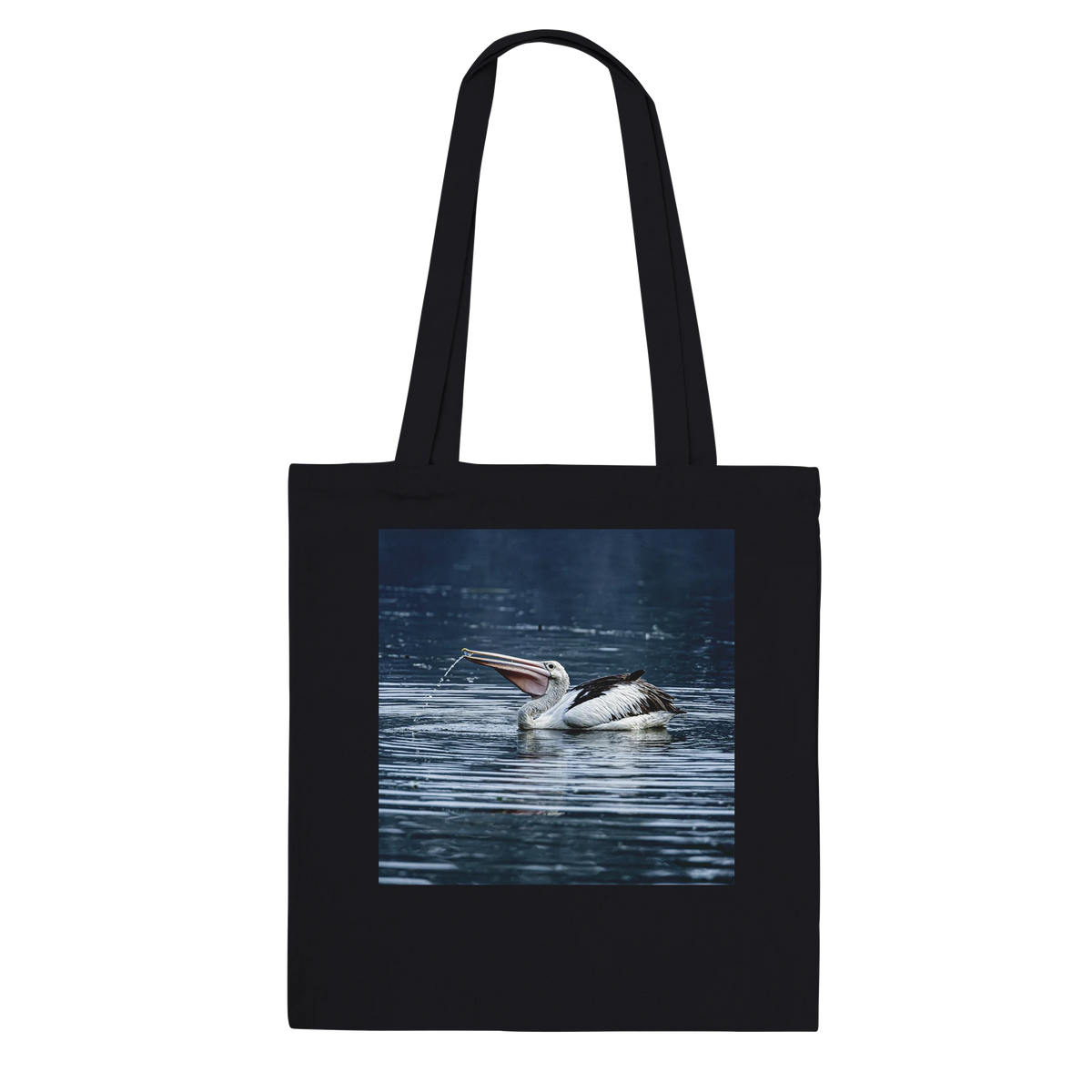 Black canvas tote bag printed with a splashing pelican photo, front view
